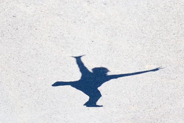 Ombra di un uomo che salta sull'asfalto — Foto Stock