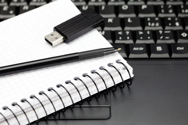 Laptop keyboard, notebook, flash drive and a pencil — Stock Photo, Image