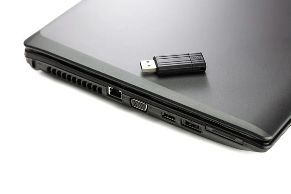 Laptop preto e flash drive isolado no branco — Fotografia de Stock