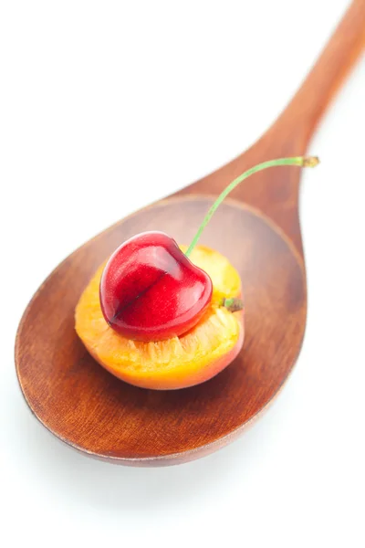 Wooden spoon, cherries and apricots isolated on white — Stock Photo, Image