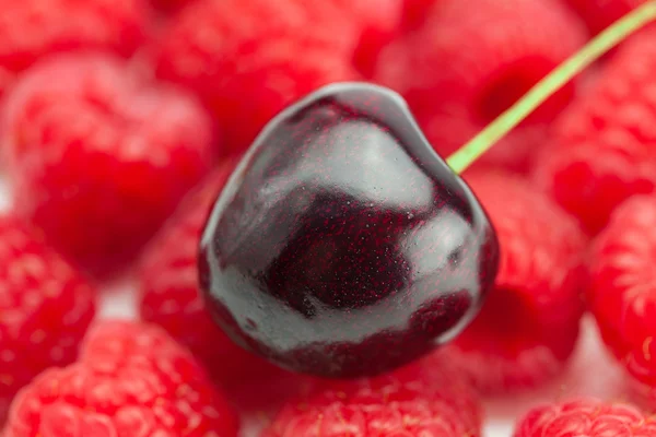 Cherry på en bakgrund av hallon — Stockfoto