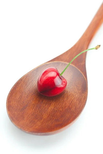 Houten lepel en cherry geïsoleerd op wit — Stockfoto