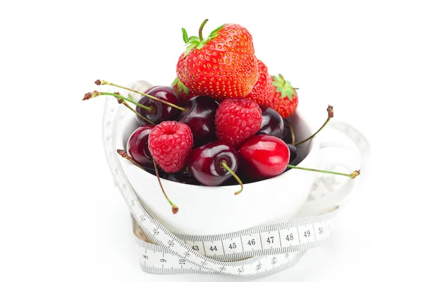 La cinta métrica, frambuesas, fresas y cerezas en un tazón es — Foto de Stock