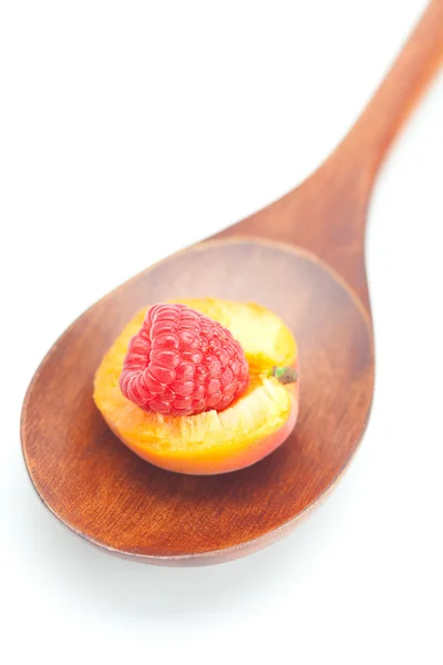 Houten lepel, framboos en abrikozen geïsoleerd op wit — Stockfoto