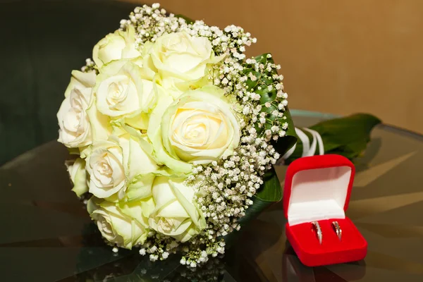 Menyasszonyi csokor és egy doboz egy üveg asztal gyűrűk — Stock Fotó