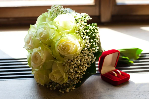 Svatební kytice a box s kroužky na okně — Stock fotografie