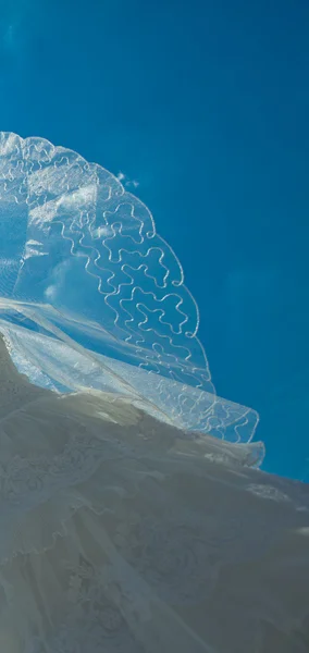 Bröllopsklänning och slöja mot den blå himlen — Stockfoto