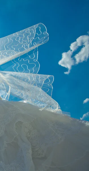 Vestido de noiva e véu contra o céu azul — Fotografia de Stock
