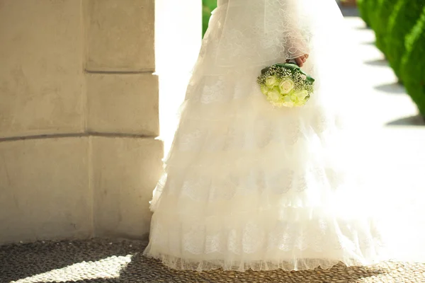 Bouquet entre les mains de la mariée sur fond de dres — Photo