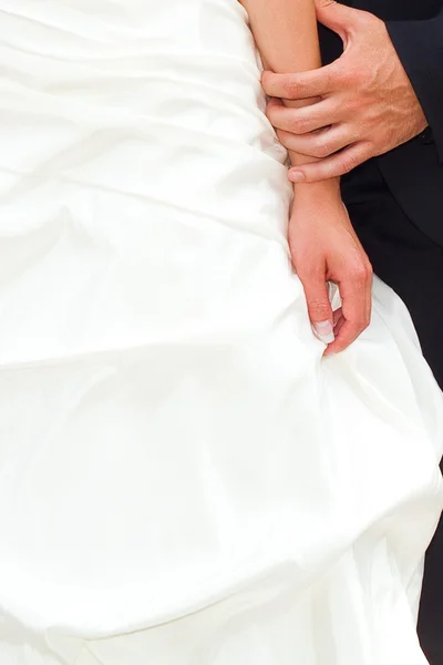 Ruce nevěsty a ženicha na pozadí svatební šat — Stock fotografie