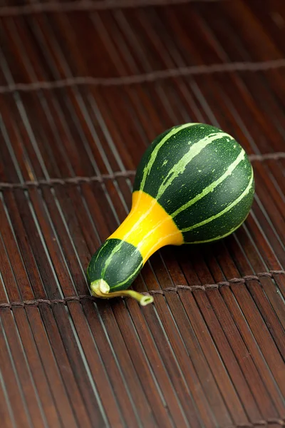 Gelb grüner Porzellan-Kürbis auf einer Bambusmatte — Stockfoto