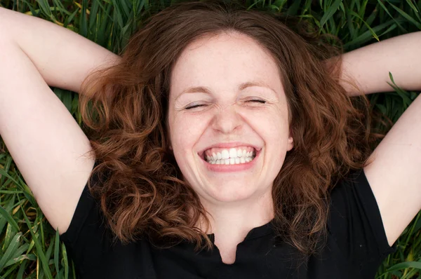 Readhead kvinnan skrattar lögn på gräset — Stockfoto