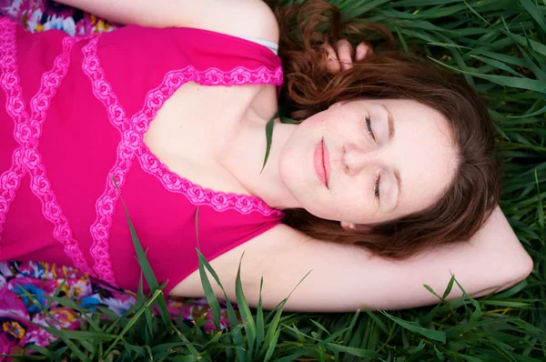 Руда жінка лежить на зеленій траві — стокове фото