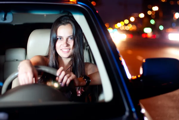 Молода жінка водить машину в нічному місті — стокове фото