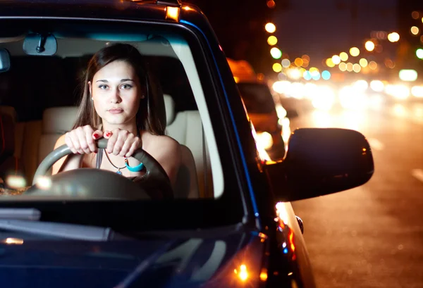 Mujer joven conduciendo coche en la ciudad de la noche — Foto de Stock
