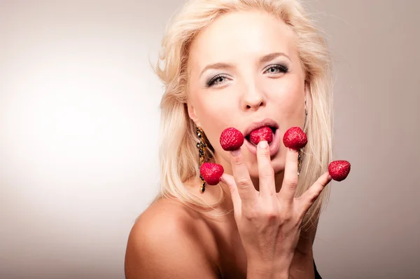 Blond kvinna äta jordgubbar från fingrar — Stockfoto