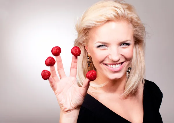Blond kvinna stick jordgubbe på fingrarna — Stockfoto
