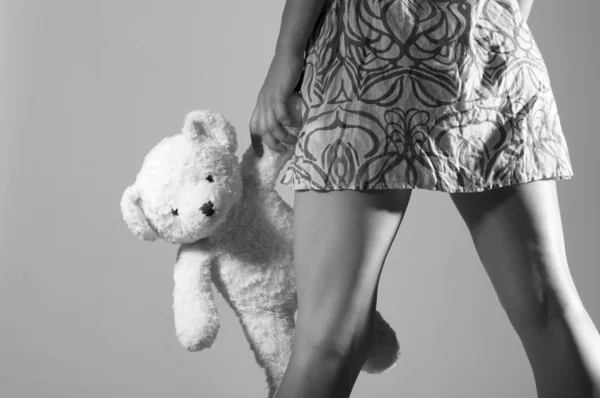 Nohy dívka hospodářství teddy bear v ruce — Stockfoto