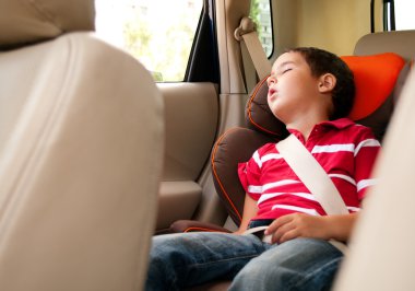 Litle boy sleeps in safe chair in car clipart