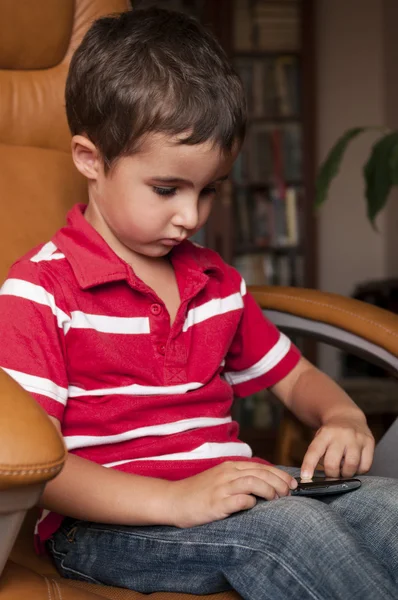 Little boy play smartphone game in leather chair — Stock Photo, Image