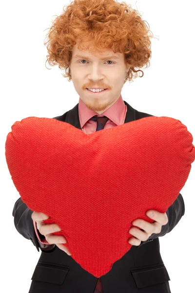 Homem bonito com travesseiro vermelho em forma de coração — Fotografia de Stock