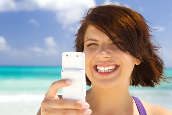 Щаслива жінка з телефоном на пляжі — стокове фото