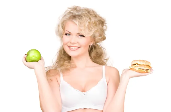 Kadın Burger ve apple arasında seçim yapma Stok Fotoğraf
