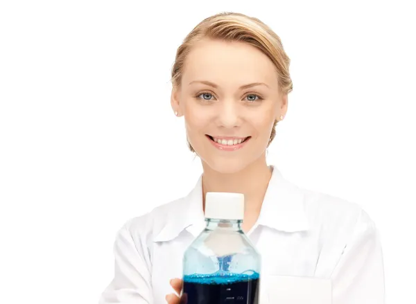 Lab worker holding up bottle with blue liquid — Stock Photo, Image