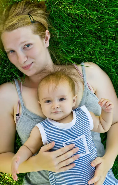 Madre y pequeño bebé acostados en la hierba — Foto de Stock