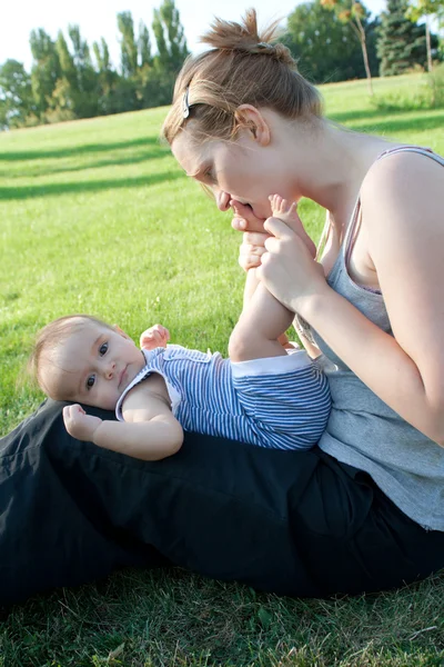 Mutter küsst oder beißt Baby Zehen — Stockfoto