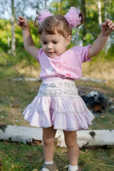 ジャンプしようとすると、ピンクの弓を持つ少女 — ストック写真