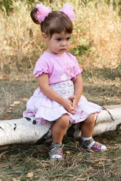 悲伤的小女孩坐在日志上 — 图库照片