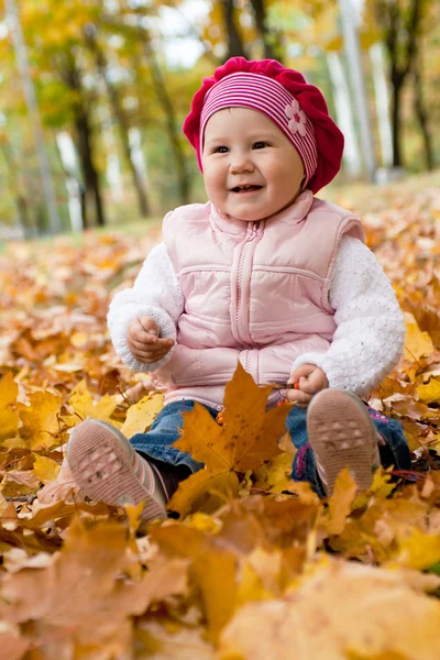 Ragazza sorridente su foglie gialle — Foto Stock