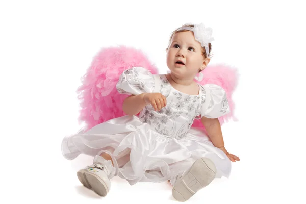 Маленькая девочка в розовых крыльях смотрит вверх — стоковое фото