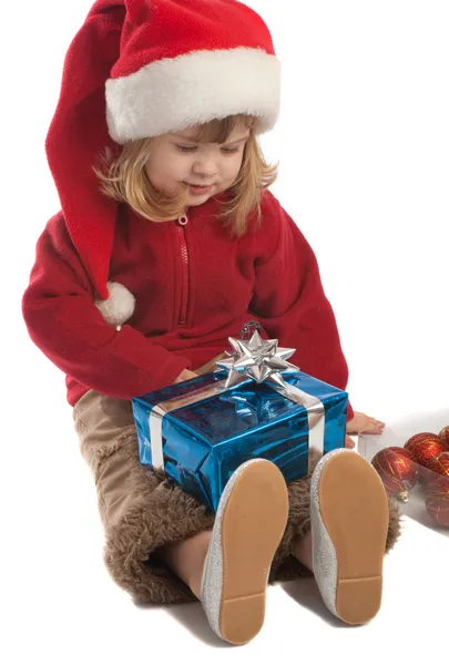 Kleine Weihnachtsmann-Helferin schaut auf Geschenkbox — Stockfoto