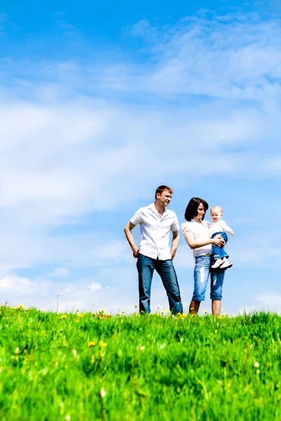 Joyeux jeune famille sur l'herbe verte au-dessus du ciel — Photo