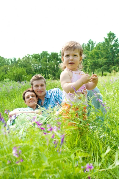 Småbarn och hennes föräldrar på ängen — Stockfoto