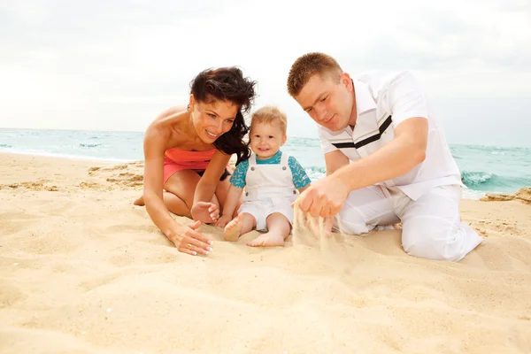 Mamma, pappa och baby på stranden — Stockfoto