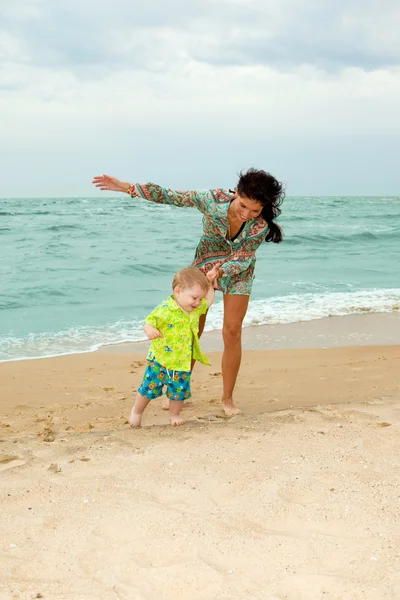 Barnet och hans mor som promenerar på stranden — Stockfoto