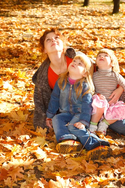 Mother and daughters in autumn leaves — Stock Photo, Image