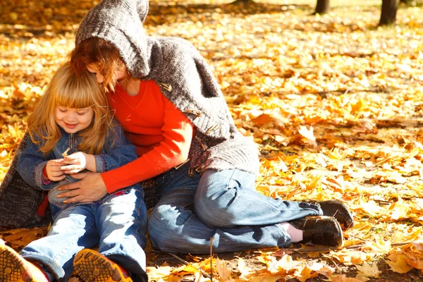 Mother and daughter in autumn leaves — Stock Photo, Image