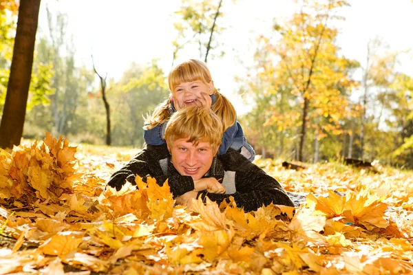 Papai e filha em folhas de outono — Fotografia de Stock