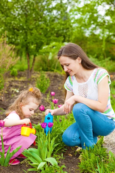 Femme avec fille arrosant des fleurs — Photo