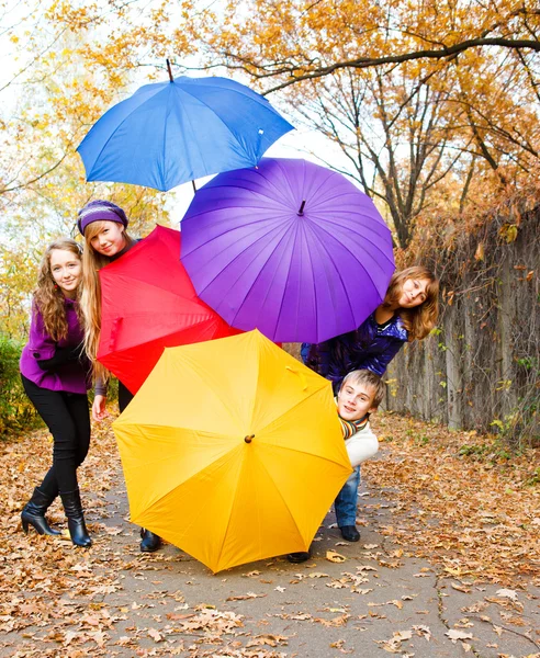 Friends hiding behind umbrellas — Stock Photo, Image