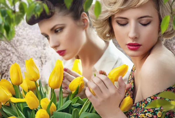Dos hermosas damas en un jardín de tulipanes — Foto de Stock