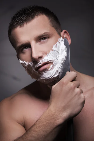 Mann rasiert sich mit großem Messer — Stockfoto