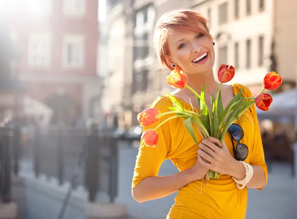 Femme souriante avec un bouquet de fleurs — Photo