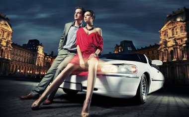 Sexy young couple in front of a limousine clipart