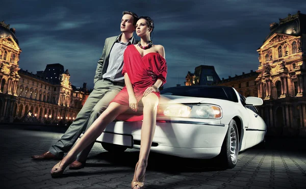 Sexy joven pareja delante de una limusina — Foto de Stock