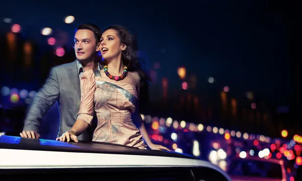 Casal elegante viajando uma limusine à noite — Fotografia de Stock